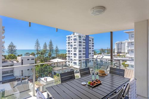 a balcony with a table and chairs and a view of the ocean at Coco Mooloolaba in Mooloolaba