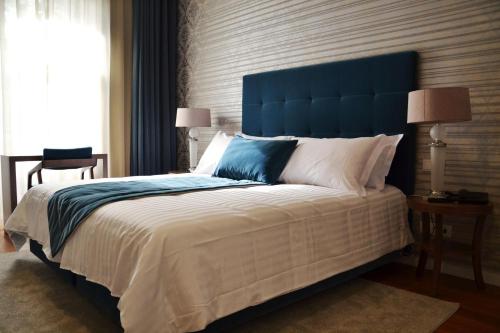 a bedroom with a large bed with a blue headboard at Hotel do Parque in Braga