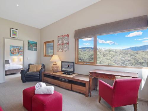 a living room with a desk with a computer and a window at Les Perrieres Chalet - Spacious 2BR Chalet l Gym l Indoor Pool l Tennis l WiFi l BBQ in Jindabyne