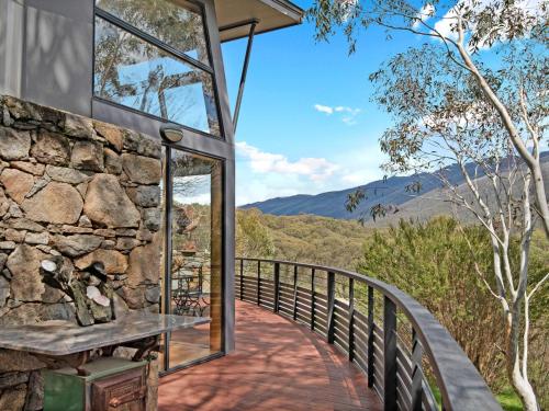 a wooden bench on a bridge with a view of the mountains at Les Perrieres Chalet - Spacious 2BR Chalet l Gym l Indoor Pool l Tennis l WiFi l BBQ in Jindabyne
