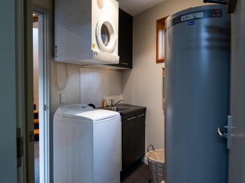 a small kitchen with a sink and a refrigerator at Les Perrieres Chalet - Spacious 2BR Chalet l Gym l Indoor Pool l Tennis l WiFi l BBQ in Jindabyne
