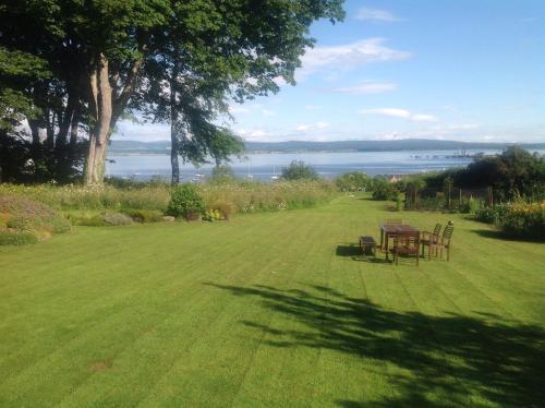 a table and chairs in a lawn with a view of the water at The Factor's House in Cromarty