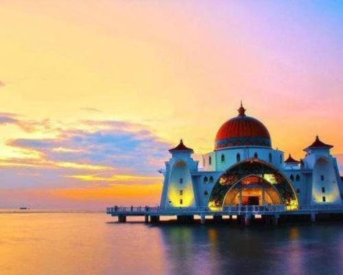 a mosque on the water with a sunset in the background at [New!] Jonker Street Loft 3BR Melaka 10PAX in Melaka