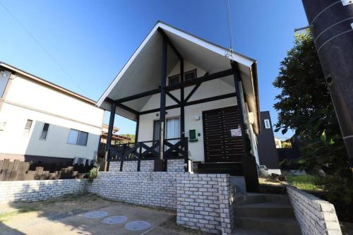a small white house with a black door and stairs at 白浜ホープヒルズ　G-62 in Kanayama
