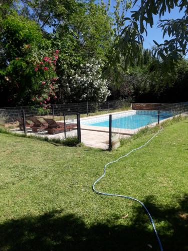 a swimming pool with a hose on the grass at La casita en el parque in Chacras de Coria