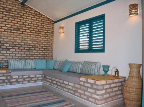 a living room with a couch and a brick wall at Wind Nomade House - São Miguel do Gostoso in São Miguel do Gostoso