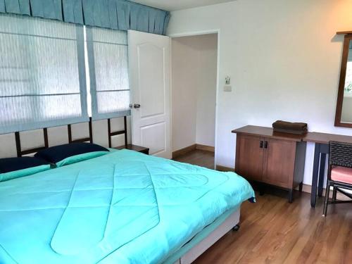 a bedroom with a blue bed and a wooden desk at Baan Talay Samran relaxing with garden view (2 BR) in Ban Khlong Khot