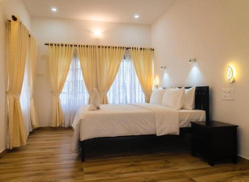 a bedroom with a bed with white sheets and curtains at The Marine Pride Beach Resort & Spa in Varkala