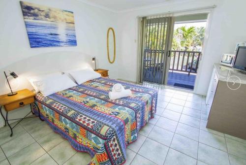 a bedroom with a bed and a balcony at Agnes Palms Accommodation in Agnes Water