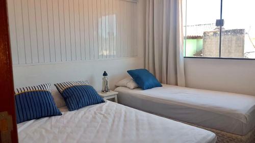 two beds in a room with a window at Apartamento Excelente in Arraial do Cabo