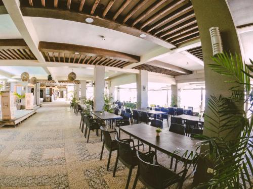 a dining room with tables and chairs and plants at Miami Heat Beach Resort powered by Cocotel in Morong