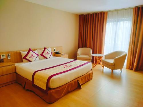 ein Hotelzimmer mit einem großen Bett und einem Stuhl in der Unterkunft VISUHA HOTEL in Hà Tiên