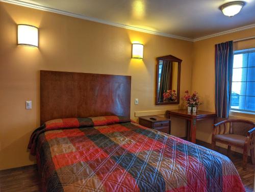 a bedroom with a large bed and a chair at Americas Best Value Inn Oxnard-Port Hueneme in Port Hueneme
