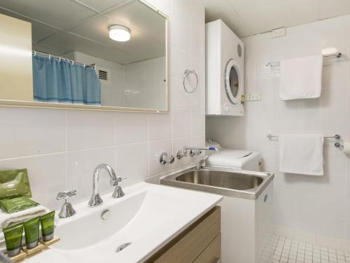 ein weißes Badezimmer mit Waschbecken und Spiegel in der Unterkunft Tanderra 10 on Park Road in Jindabyne