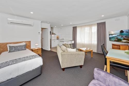 Habitación de hotel con cama y sala de estar. en Fawkner Executive Suites & Serviced Apartments, en Melbourne