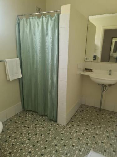 a bathroom with a shower curtain and a sink at Valley View Motel in Murrurundi
