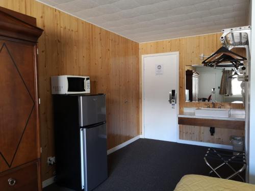 a kitchen with a refrigerator and a microwave on top of it at Travel Inn Hearst in Hearst