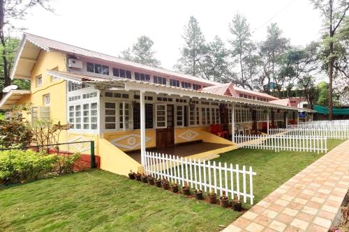 a building with a white fence in front of it at Citadel Resort in Panchgani