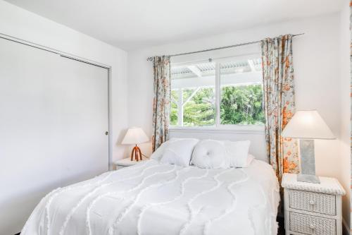 a white bedroom with a white bed with a window at Volcano Cottage in Volcano