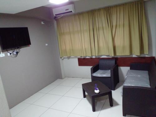 ein Wohnzimmer mit einem TV, einem Stuhl und einem Tisch in der Unterkunft Sunseekers Outrigger Hotel in Suva