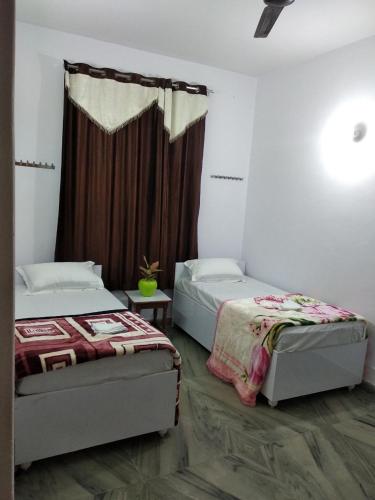 a bedroom with two beds and a window at Videep house in Kānpur