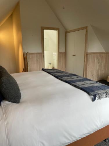 a large white bed in a room with a door at Little Chalet Daylesford in Daylesford