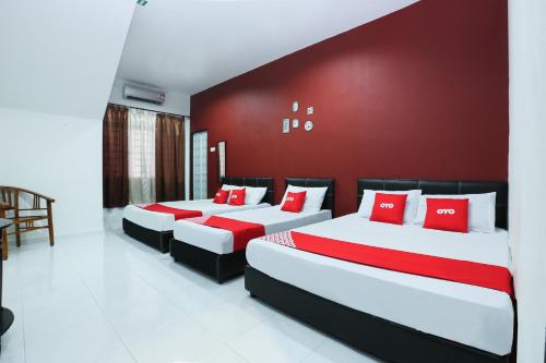 duas camas num quarto com uma parede vermelha em OYO 90274 Wadi Isfa Inn em Kota Bharu