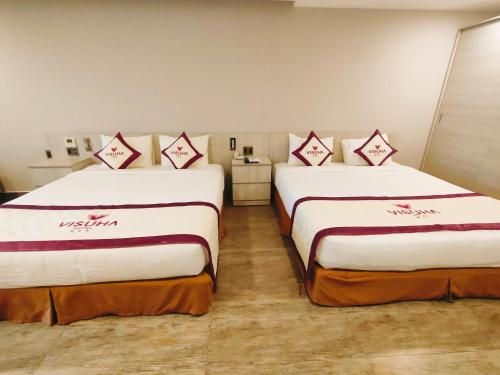 two beds in a hotel room with white sheets at VISUHA HOTEL in Ha Tien