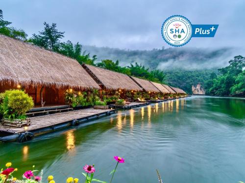a river with a row of houses and flowers at River Kwai Jungle Rafts in Sai Yok