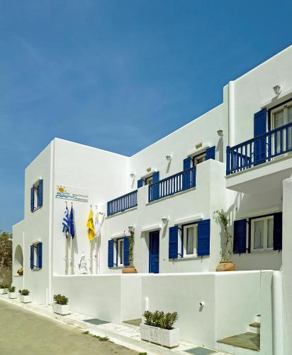 a white building with blue doors and windows at Mata's Apartments in Tinos Town