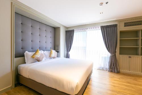 a bedroom with a large white bed with a large window at Thea, Executive Suite Serviced Apartment in Ekamai in Bangkok