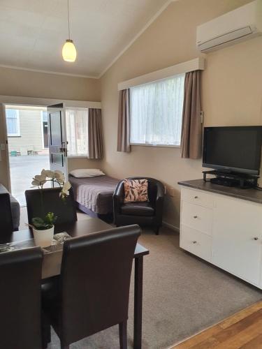 a living room with a bed and a desk with a television at Gardner Court Motel in Napier