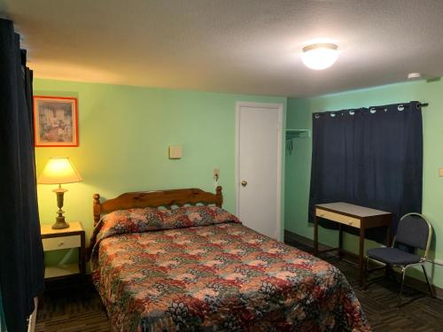 a bedroom with a bed and a table and a lamp at Tour Inn Motel in Howard City