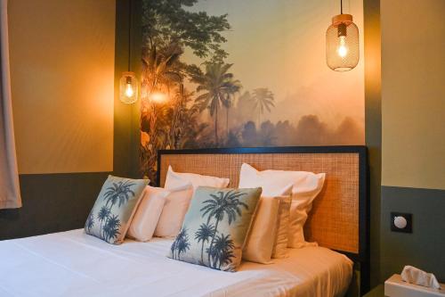 a bedroom with a bed with white pillows and a painting at Hôtel Le Pavillon de Saint-Lô in Saint Lo