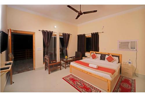 a bedroom with a bed and a desk and a television at FabHotel Corbett Green View Garden and Stay in Rāmnagar