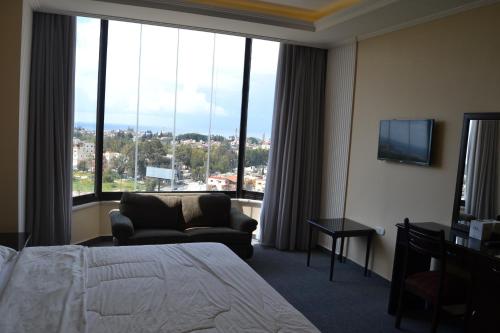 a hotel room with a bed and a chair and a large window at Platinum Hotel in Soûr