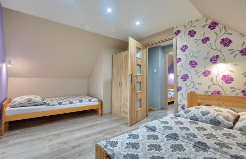 Un dormitorio con 2 camas y una pared con flores púrpuras. en Domki całoroczne ,,DOLINA BIESZCZAD", en Polańczyk