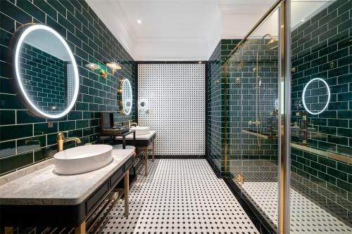 ein Badezimmer mit 2 Waschbecken und einer Dusche mit grünen Fliesen in der Unterkunft Hotel Indigo Heilong Lake, an IHG Hotel in Meishan