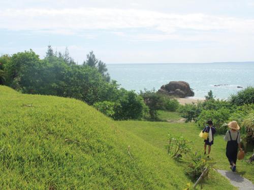 two people walking down a path near the ocean at Villa Kukuru in Ginoza