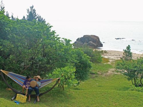 two people sitting in a hammock looking at the ocean at Villa Kukuru in Ginoza