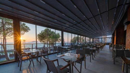 a dining room with tables and chairs and windows at Sundia Exclusive By Liberty Fethiye Adults Only in Fethiye