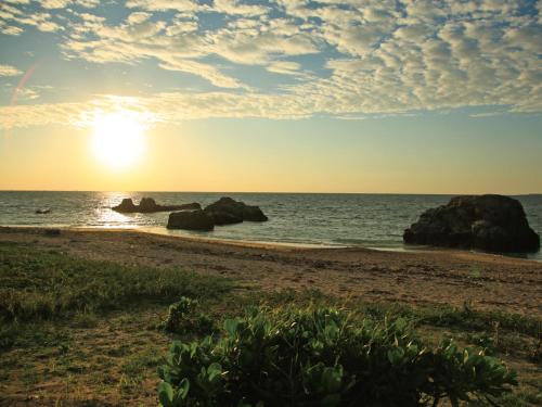 a sunset on a beach with rocks in the water at Villa Kukuru in Ginoza