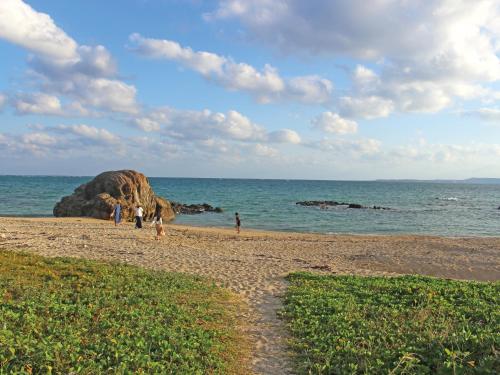 a group of people walking on a beach near the ocean at Villa Kukuru in Ginoza