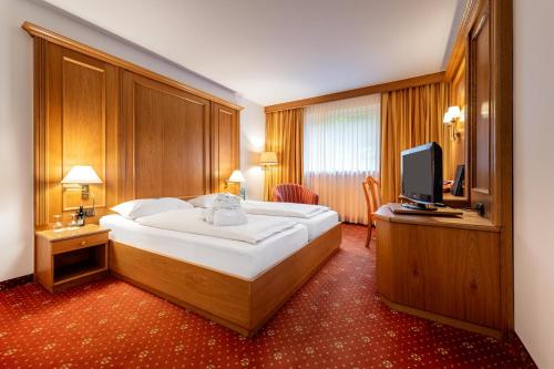 um quarto com uma cama grande e uma televisão em VILA VITA Burghotel Dinklage em Dinklage