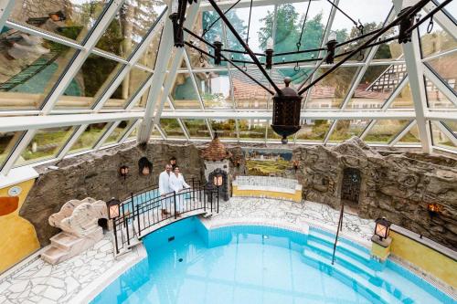 two people standing on a balcony next to a swimming pool at VILA VITA Burghotel Dinklage in Dinklage