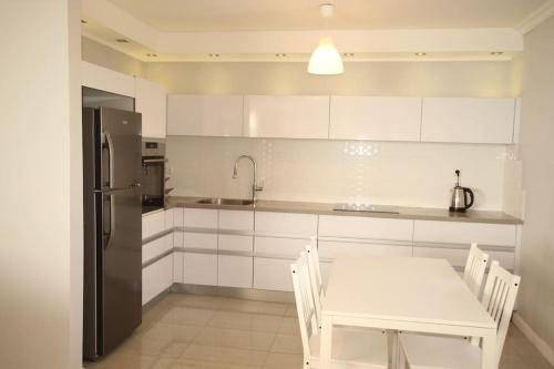 a kitchen with a white table and a refrigerator at Royal Aparatment on the Sea , Blvd Nitza 34 in Netanya