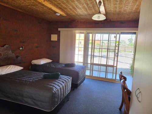 Habitación de hotel con 2 camas y ventana en Foundry Palms Motel, en Charlton
