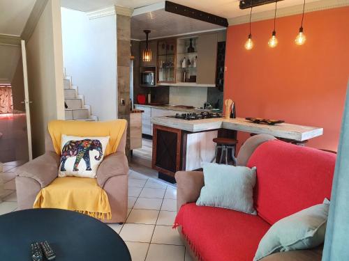 a living room with a red couch and a kitchen at Hacienda Holiday Home in Richards Bay