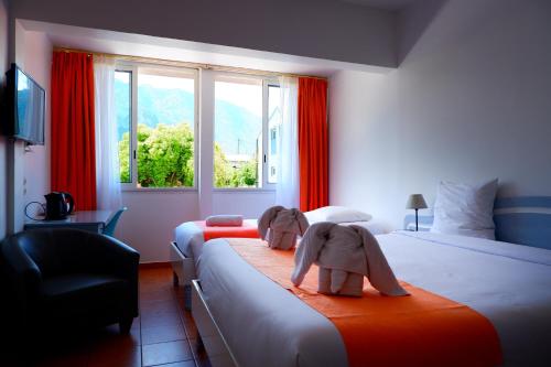 een hotelkamer met 2 bedden en handdoeken erop bij Hôtel Du Cirque in Cilaos