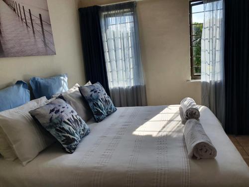 a white bed with pillows and towels on it at Hacienda Holiday Home in Richards Bay